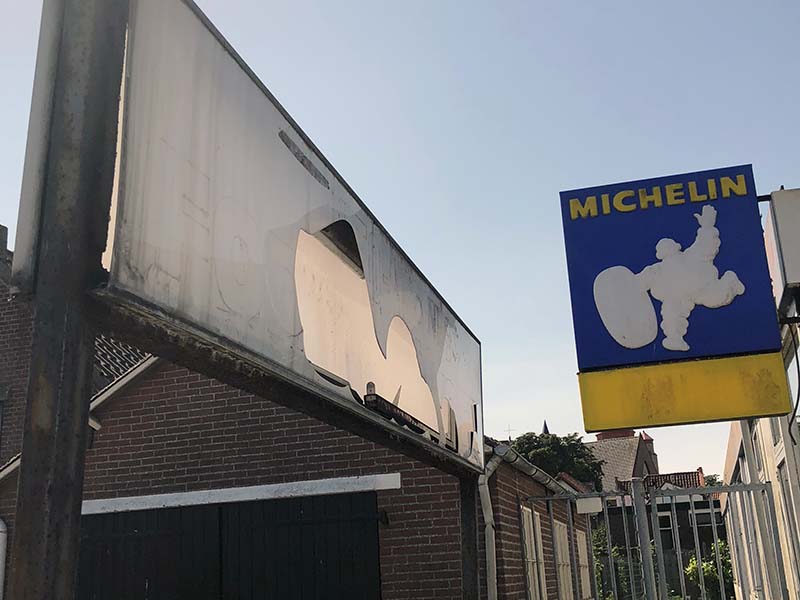 Beschadigde en verouderde reclameborden aan en bij een leegstaande pand.